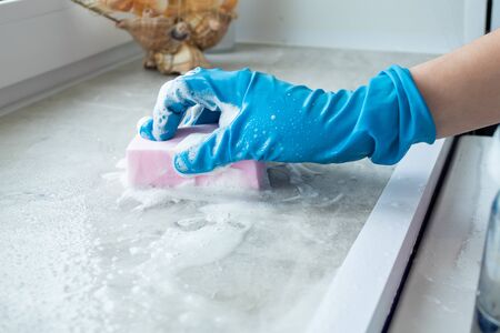 the girl washes the windowsill with a sponge and a special liquid. Cleaning the bathroom with...