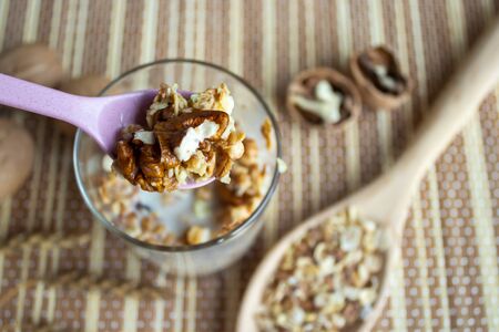 Muesli with nuts in a glass with a spoon. Healthy and healthy food on a wooden tableの写真素材