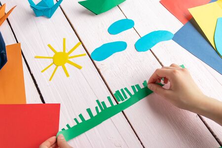 A girl makes an application of paper on a wooden table. The girl is playingの写真素材