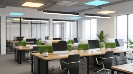 A blurred image of a modern office with desks computers and natural light creating a professional settingの素材