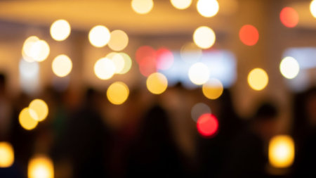 A blurred image of a crowd with bokeh lights creating a warm and festive atmosphere in an indoor settingの素材