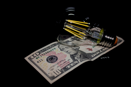 light bulb on money on a black backgroundの写真素材