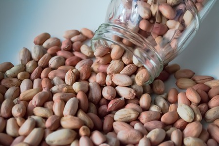 peanuts in a glass jar on a white backgroundの写真素材