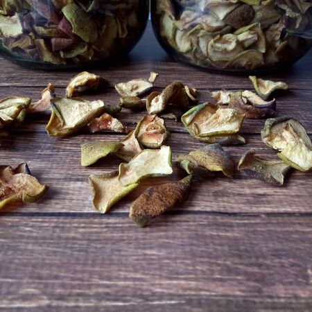 Organic dried pears on a wooden table on the background of glass container. Fruit chips. Love the...
