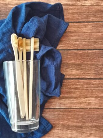 A family set of four wooden toothbrushes in a glass on blue fabric with copy spaceの写真素材