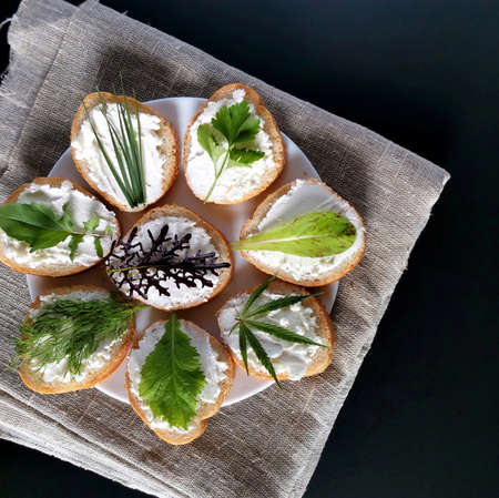 useful sandwiches with different greens and cheese on the burlap and a dark background. square photo の写真素材