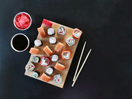 sushi with ginger and soy sauce on a wooden plank on black background. horizontal High quality photo...