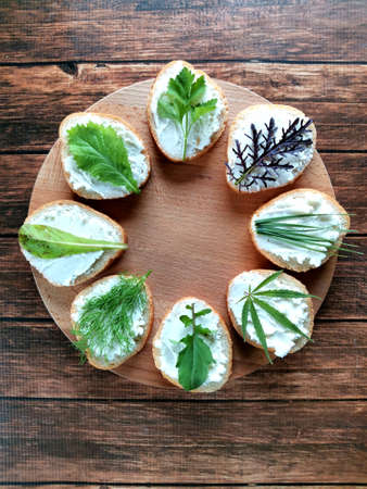 baguette, cheese and fresh greens in the form of delicious sandwiches on a wooden plank