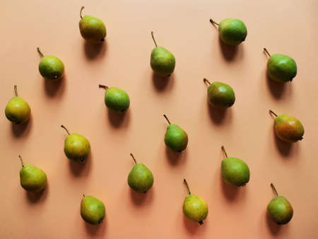 Ripe juicy garden pears on orange background. Food pattern with pears