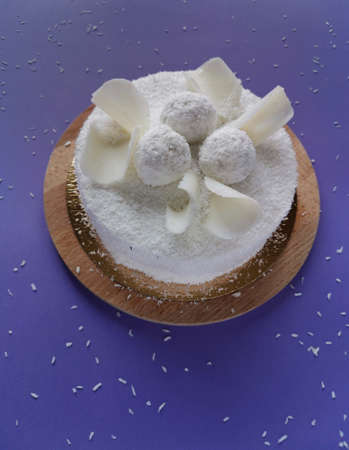 Coconut cake with white chocolate on a a lilac background