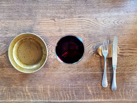 an empty plate and a glass of wine on a wooden table. waiting for lunch or dinner
