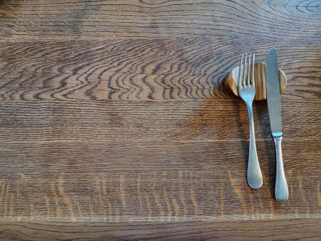 fork and knife on an empty wooden table. waiting for lunch or dinner