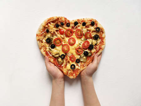 a child holds a heart shaped pizza made with his own hands. February 14 and moms day holiday conceptの写真素材