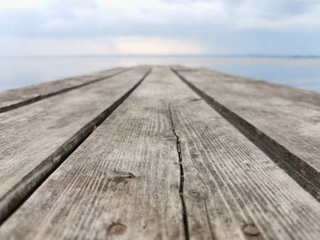 an old wooden bridge against the background of water and skyの写真素材