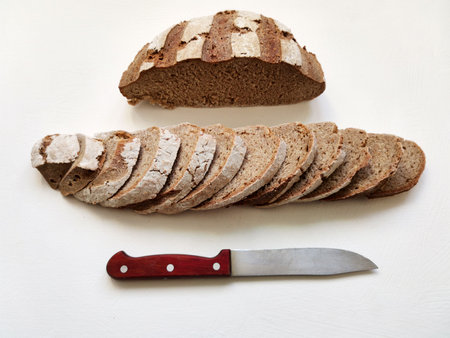 cutting rye bread in a row and a knife on a white background