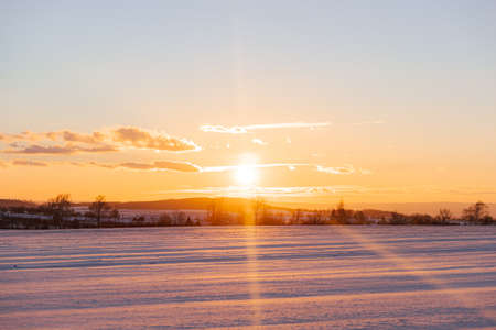 Winter colorful landscape with snowy field at pastel sunset