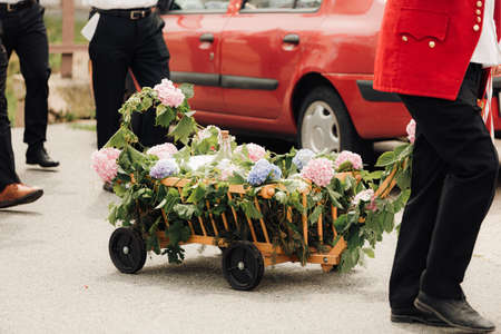 A man in a red jacket carries a cart with flowers.の写真素材