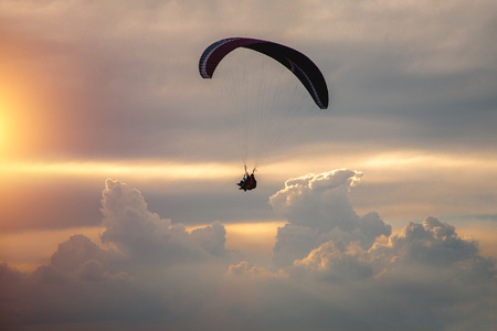 Boy and girl flying on a paraglider on a background of clouds.の写真素材