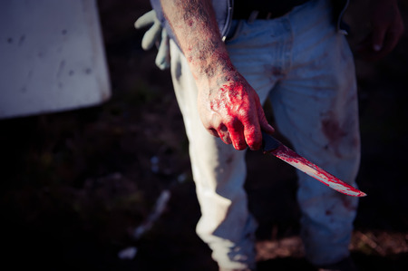 The farmer holds the knife in the blood