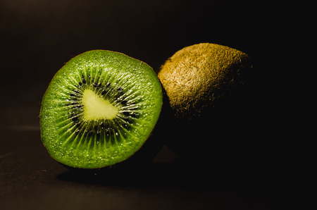 Fresh kiwi close up with drops of water on an old wooden table.の写真素材