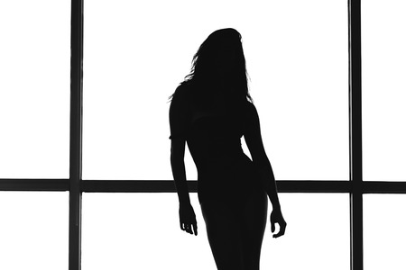Silhouette of the woman with his hands on a background of white glassの写真素材