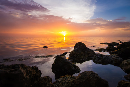 Rocky beach with calm sea during the sunset.の写真素材