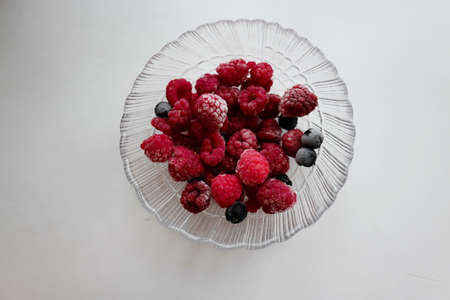 Frozen raspberries and chokeberries in a glass bowl