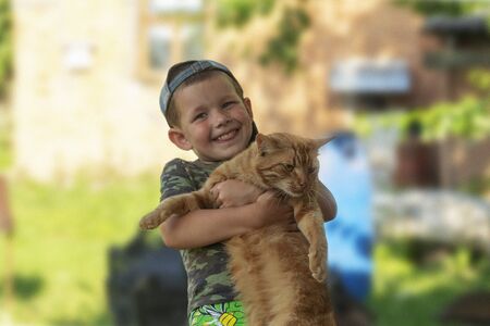 Funny boy hugging a cat with lots of love. Portrait of child holding on hands a big cat. playing with a cat.の写真素材