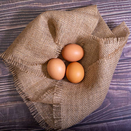 Heap of brown chicken eggs in a nest on wooden background.の写真素材