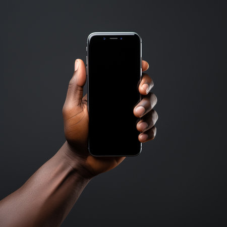 Close up of a black man's hand holding mobile phone with blank screen on dark backgroundの素材