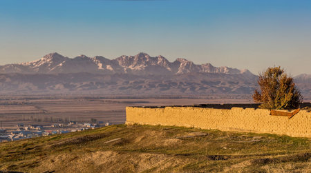 Long clay fence against the backdrop of snowy mountainsの写真素材