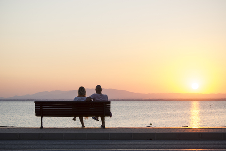Couple of Tourist Sitting on Bench Watching the Sunset in La Manga, Mar Menor Side, Cabo de Palos, Cartagena and San Javier, Murcia, Spain, Europeの写真素材