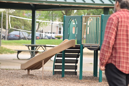 sad and lonely man looks at children's slide at the playgroundの写真素材