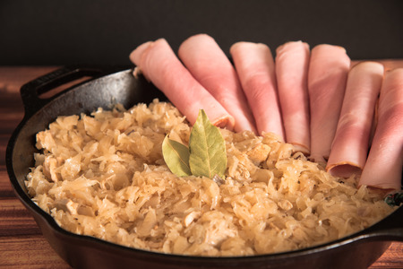 homemade braised sauerkraut in a frying pan on a wooden backgroundの写真素材
