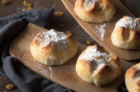 Homemade Hot Cross buns with raisins on a wooden board