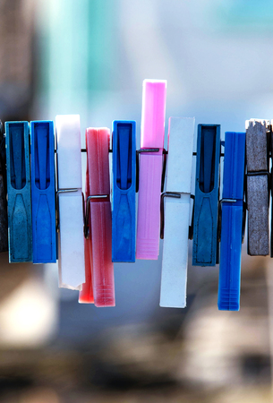 Colorful clothespin hanging on a rope. Plastic and wooden clothespins.