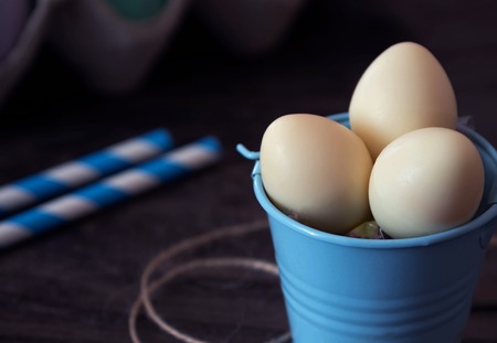 Chocolate white candy eggs in bucket. On a wooden background. Easter eggsの写真素材