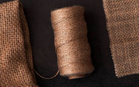 Natural jute twine roll, burlap on black background. Supplies and tools for handmade hobby leisure.