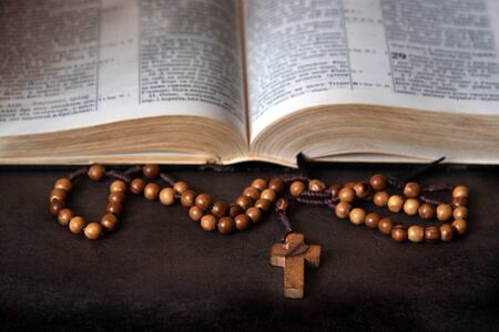 Wooden rosary and open Bible in the background.の写真素材