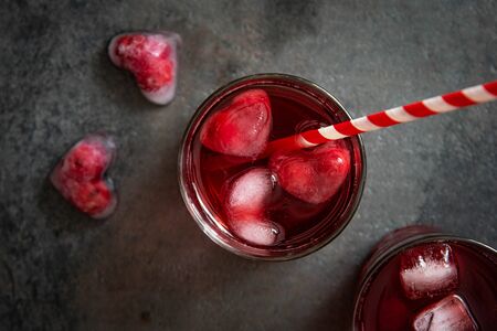 Cranberry cocktail with heart shaped ice cubes on a dark background. Top view.の写真素材