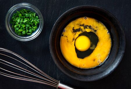 Beaten egg yolks in a bowl on a dark background.の写真素材
