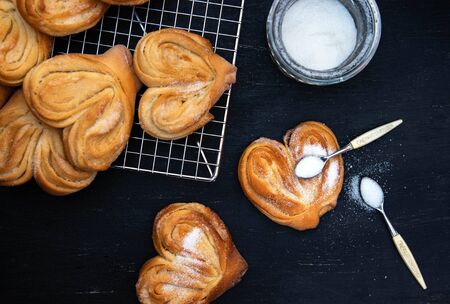 Homemade sugar buns on a cooling rack with sugar for sprinkling. Palmiers, elephant ear, puff pastry...
