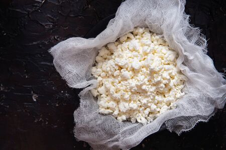 Fresh cottage cheese on gauze on a black background.の写真素材