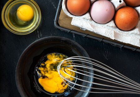 Beaten egg yolks in a bowl on a dark background.の写真素材