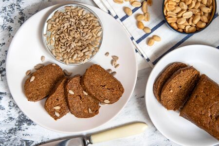 Homemade halva with peanuts and sunflowers on a white plate. Top view