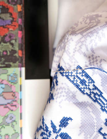 A close up of a cross stitch embroidery. Cross-stitch ornament and book with embroidered ornaments.