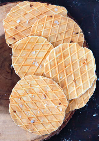 Round salty waffles, crunchy snacks on wooden background.