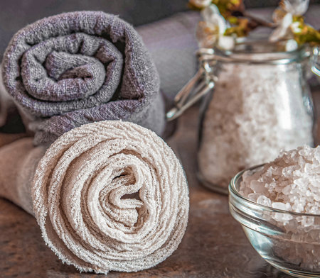 Beauty spa treatment and relax concept. Towel, sea salt and essential oils on a dark background.の写真素材