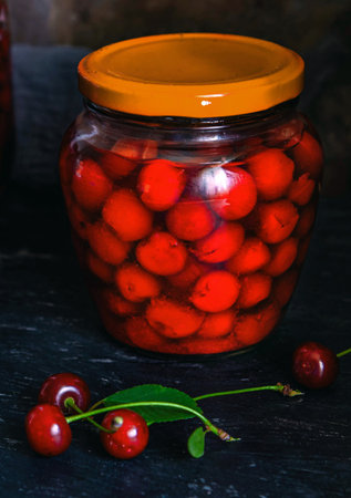Homemade cherry preserves. Fresh pitted cherries in sugar syrup in a glass jar. Canned organic food from the garden.の写真素材