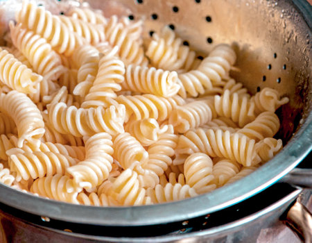 Fusilli pasta in a stainless steel colander on backgroundの写真素材